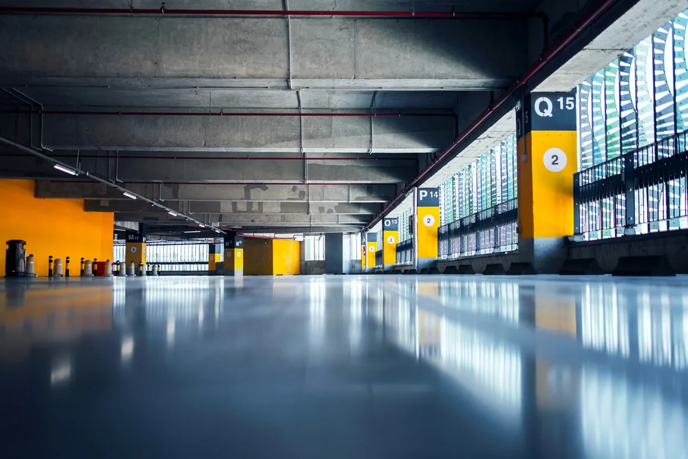 A smooth, reflective coated floor in a spacious parking garage.